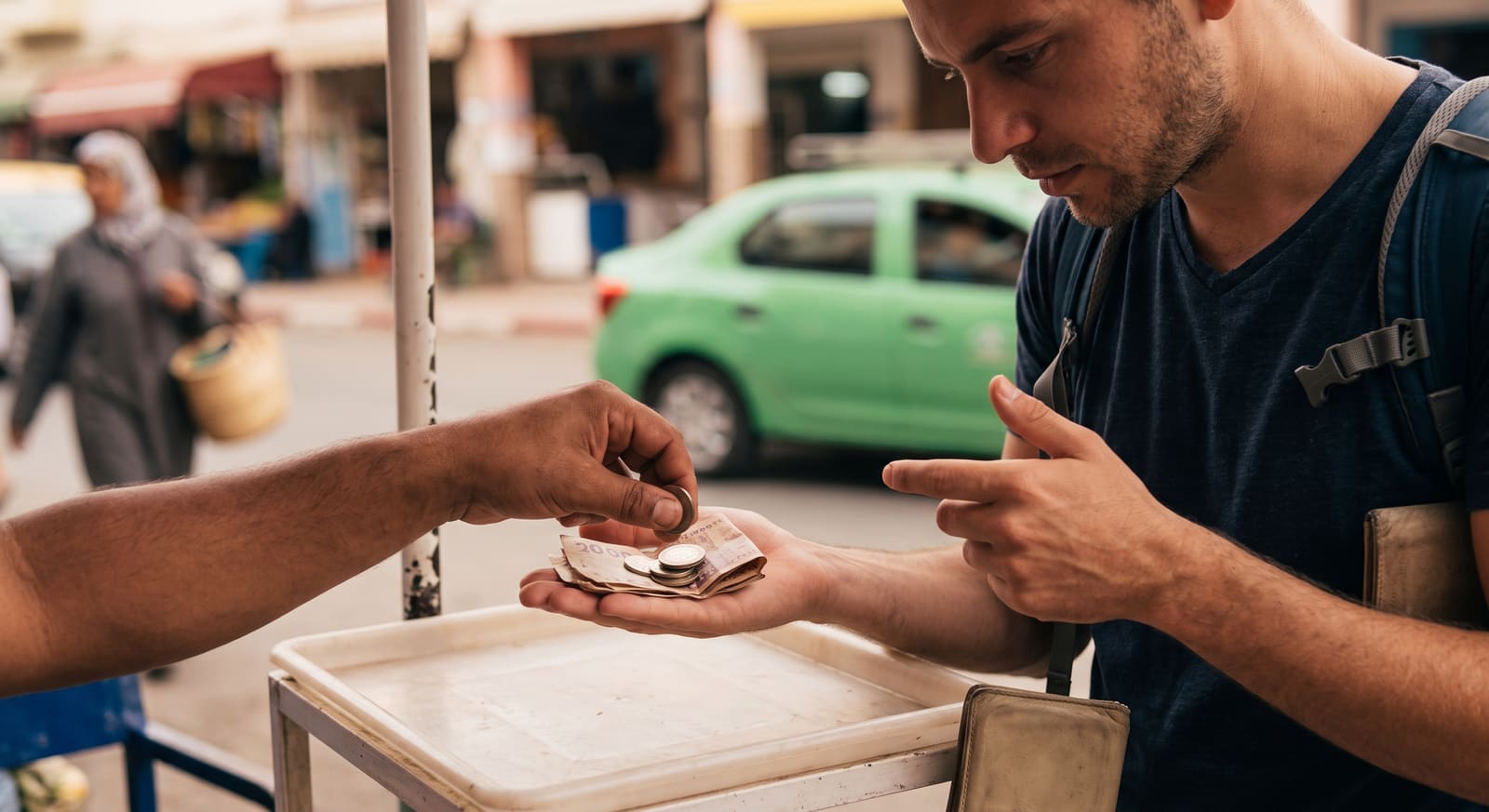 A tourist counting change at a market stall in Agadir, a habit worth building on a Teefun-planned trip.